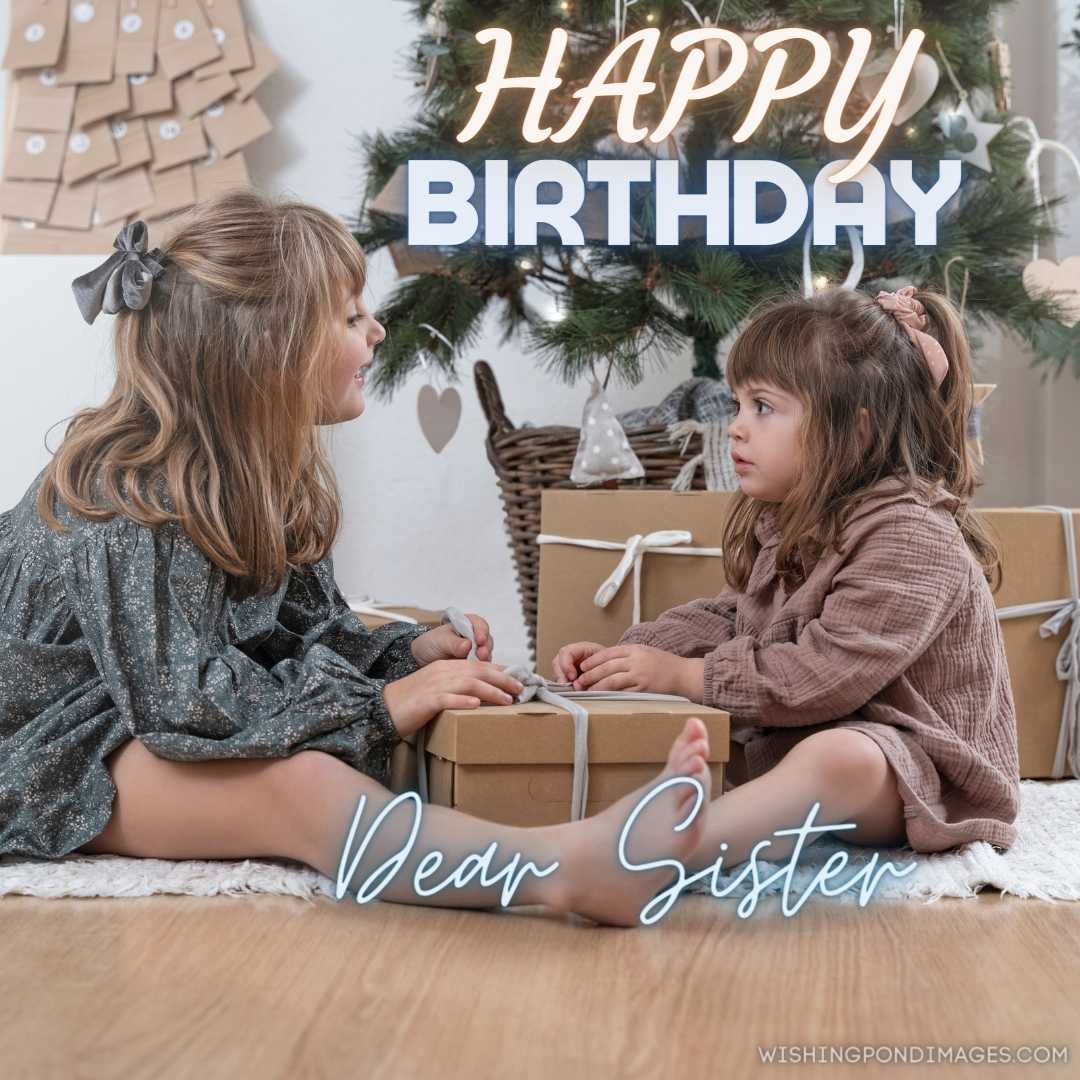 Two little sisters opening a gift near the Christmas tree at home. Happy Birthday Sister Images